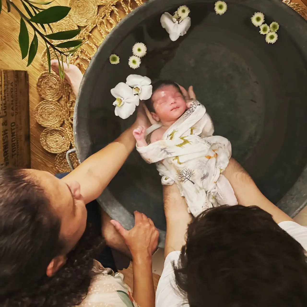 Un nouveau-né dans son Bain Douce Naissance®, entouré de fleurs